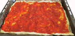 Tomatensoße auf den Pizzaboden verteilen